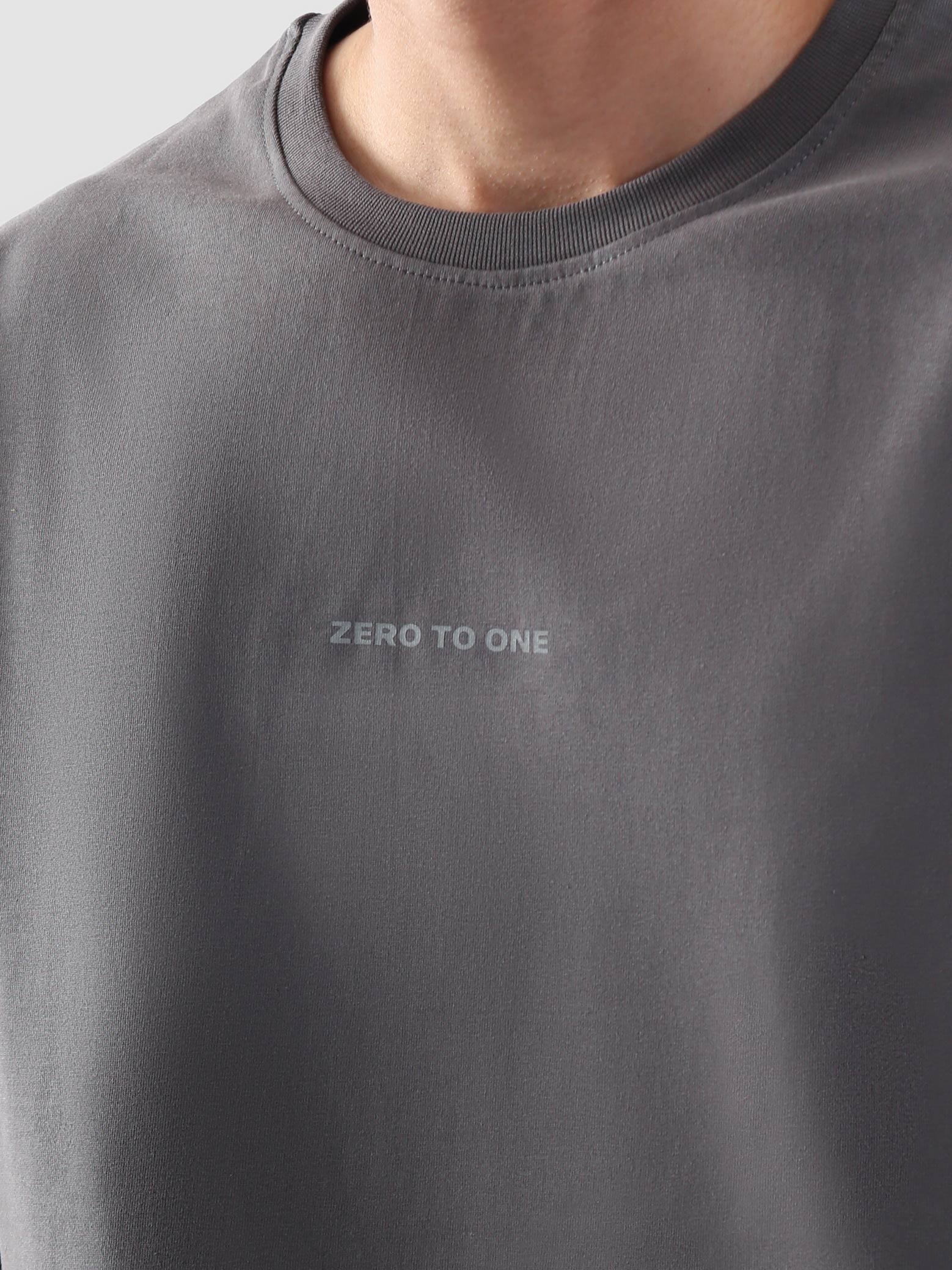 Model wearing stone grey oversized t-shirt for women in Pakistan, styled with wide-leg blue denim jeans – Groovy streetwear graphic tee with relaxed fit and drop shoulder design