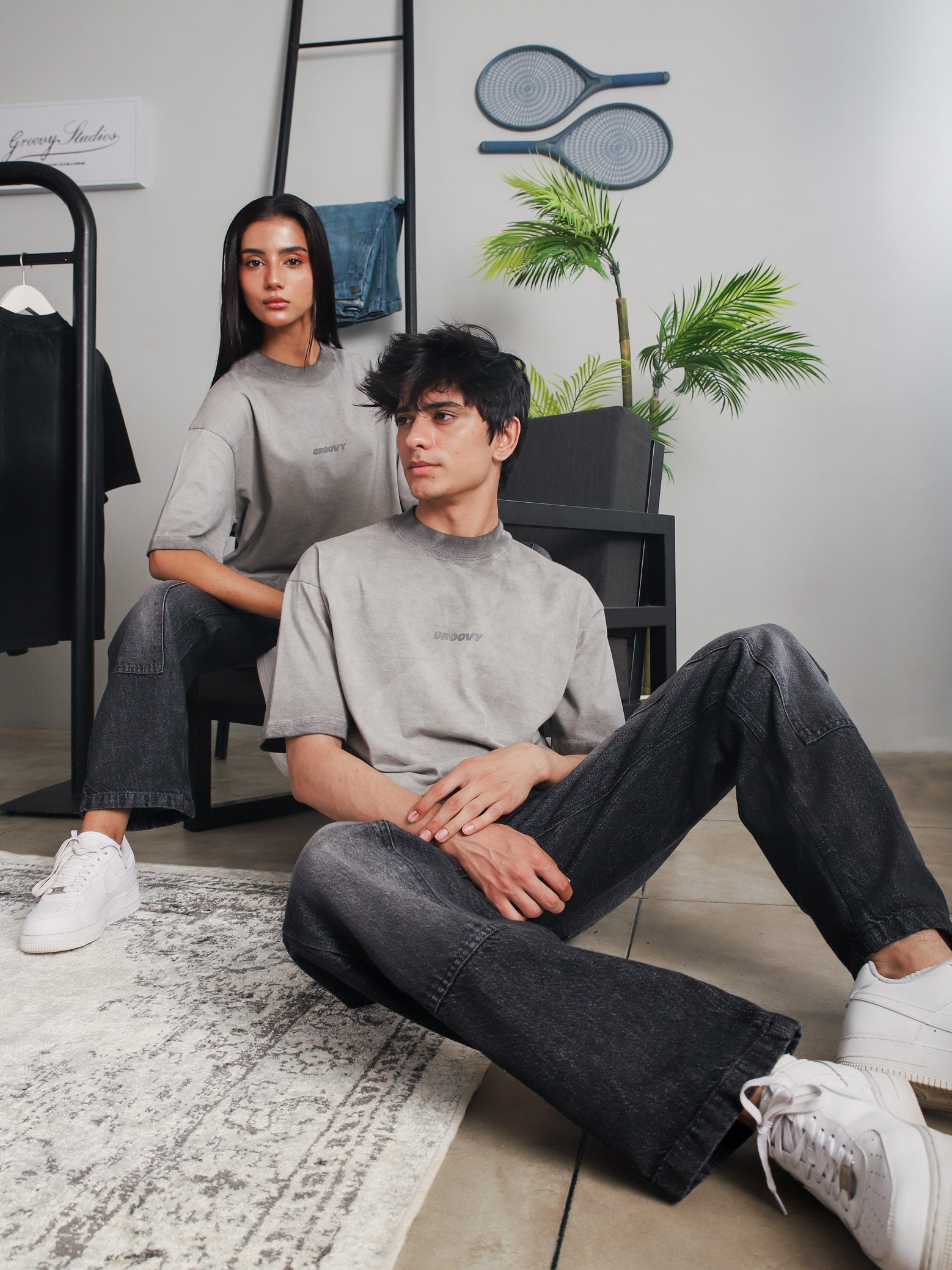 Two models wearing GROOVY Oil Fade Blank t-shirts styled with washed denim, showcasing the gradient oil-dyed texture in a clean indoor studio setup.

