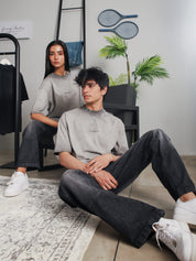 Two models wearing GROOVY Oil Fade Blank t-shirts styled with washed denim, showcasing the gradient oil-dyed texture in a clean indoor studio setup.
