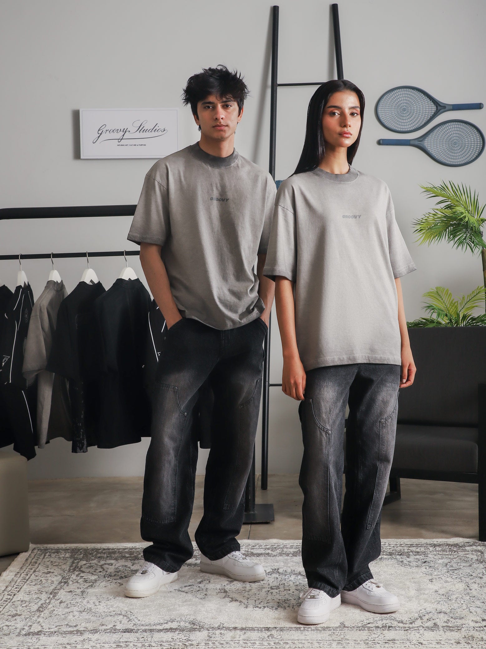 Two models wearing GROOVY Oil Fade Blank t-shirts styled with washed denim, showcasing the gradient oil-dyed texture in a clean indoor studio setup.
