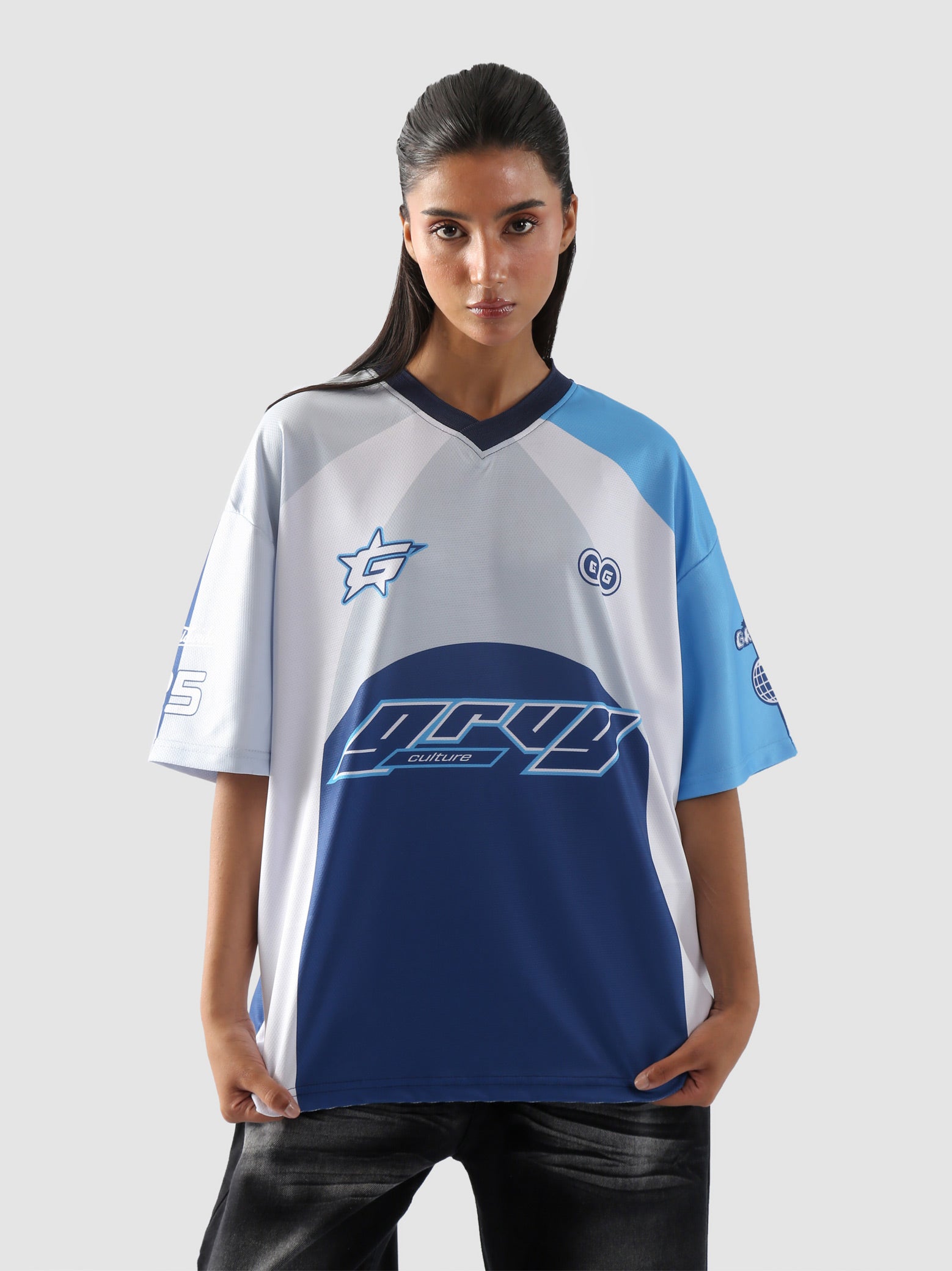 Woman wearing oversized blue and white racing jersey with bold graphics – Groovy Culture unisex streetwear shot in lifestyle indoor setup Pakistan
