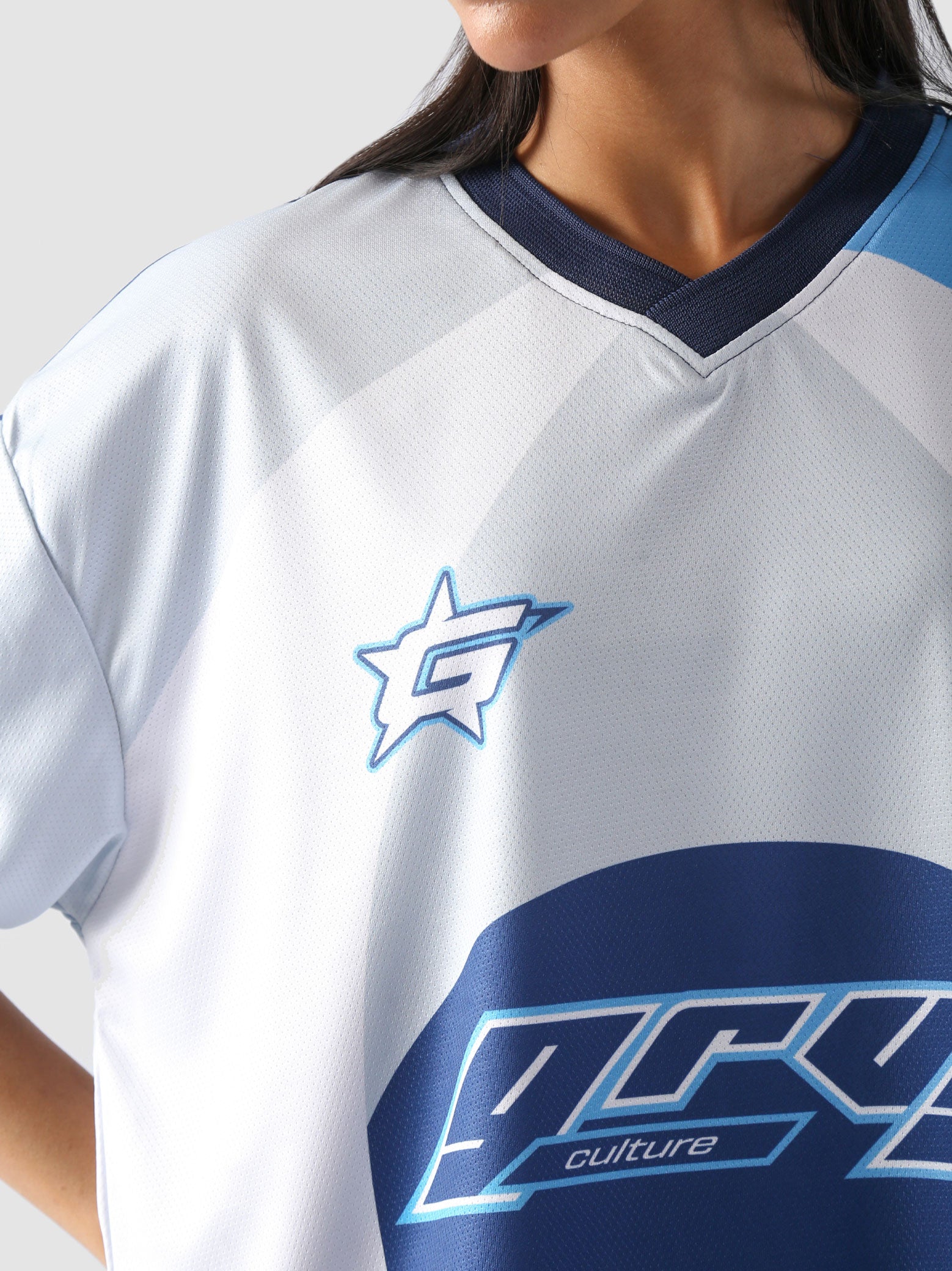 Woman wearing oversized blue and white racing jersey with bold graphics – Groovy Culture unisex streetwear shot in lifestyle indoor setup Pakistan
