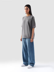 Model wearing stone grey oversized t-shirt for women in Pakistan, styled with wide-leg blue denim jeans – Groovy streetwear graphic tee with relaxed fit and drop shoulder design