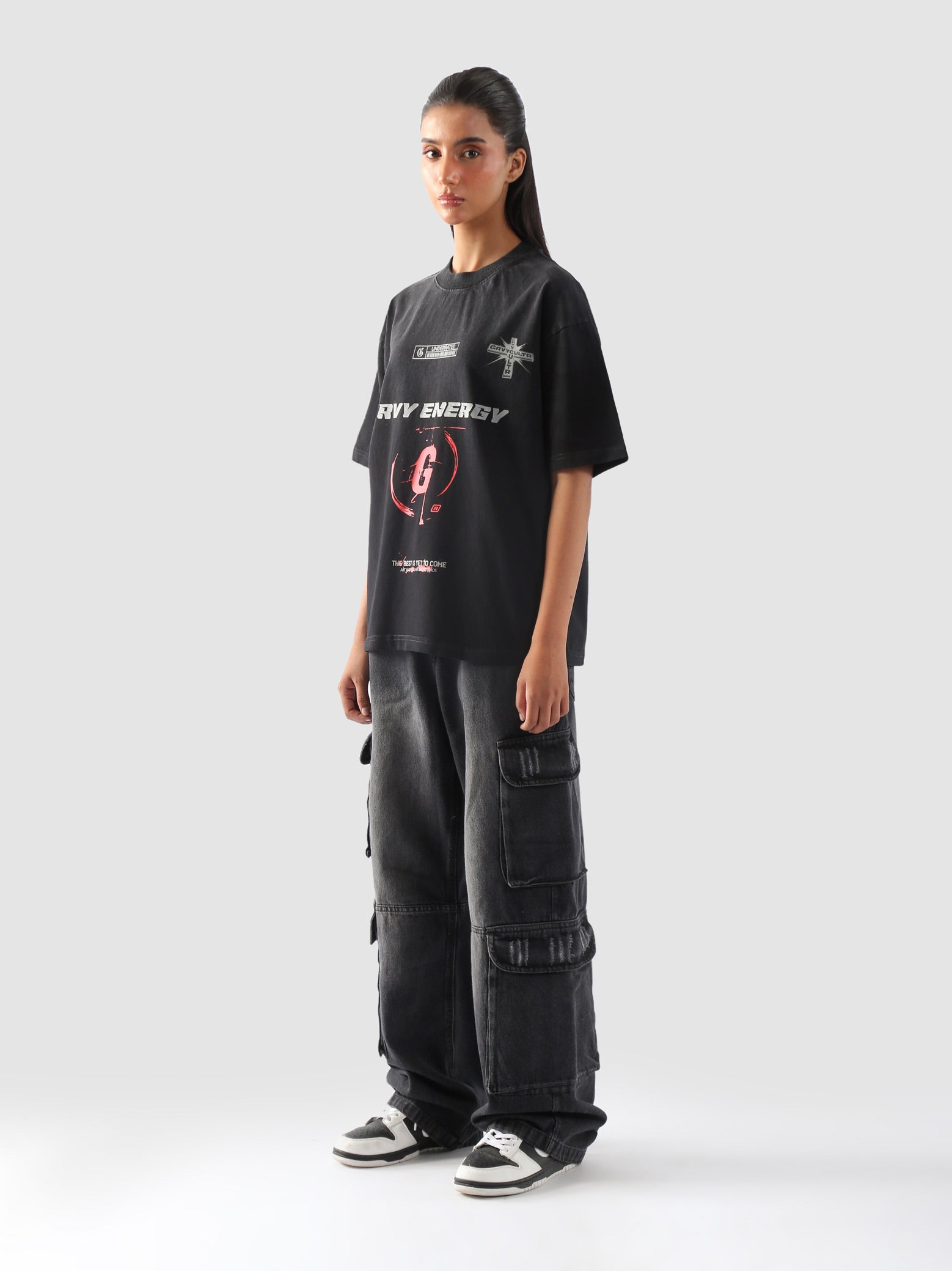 Side angle of female model showcasing the bold fit and statement design of the "GROOVY Energy" oversized t-shirt paired with street cargo pants.