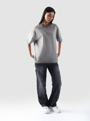 Model wears the Oil Fade Blank tee paired with faded black utility trousers, showcasing the garment’s unisex silhouette and gradient wash effect.

