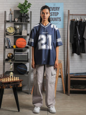 Front view of female model wearing GROOVY All Stars Basketball Jersey in navy blue, standing in a lifestyle setup with basketball and chess props.