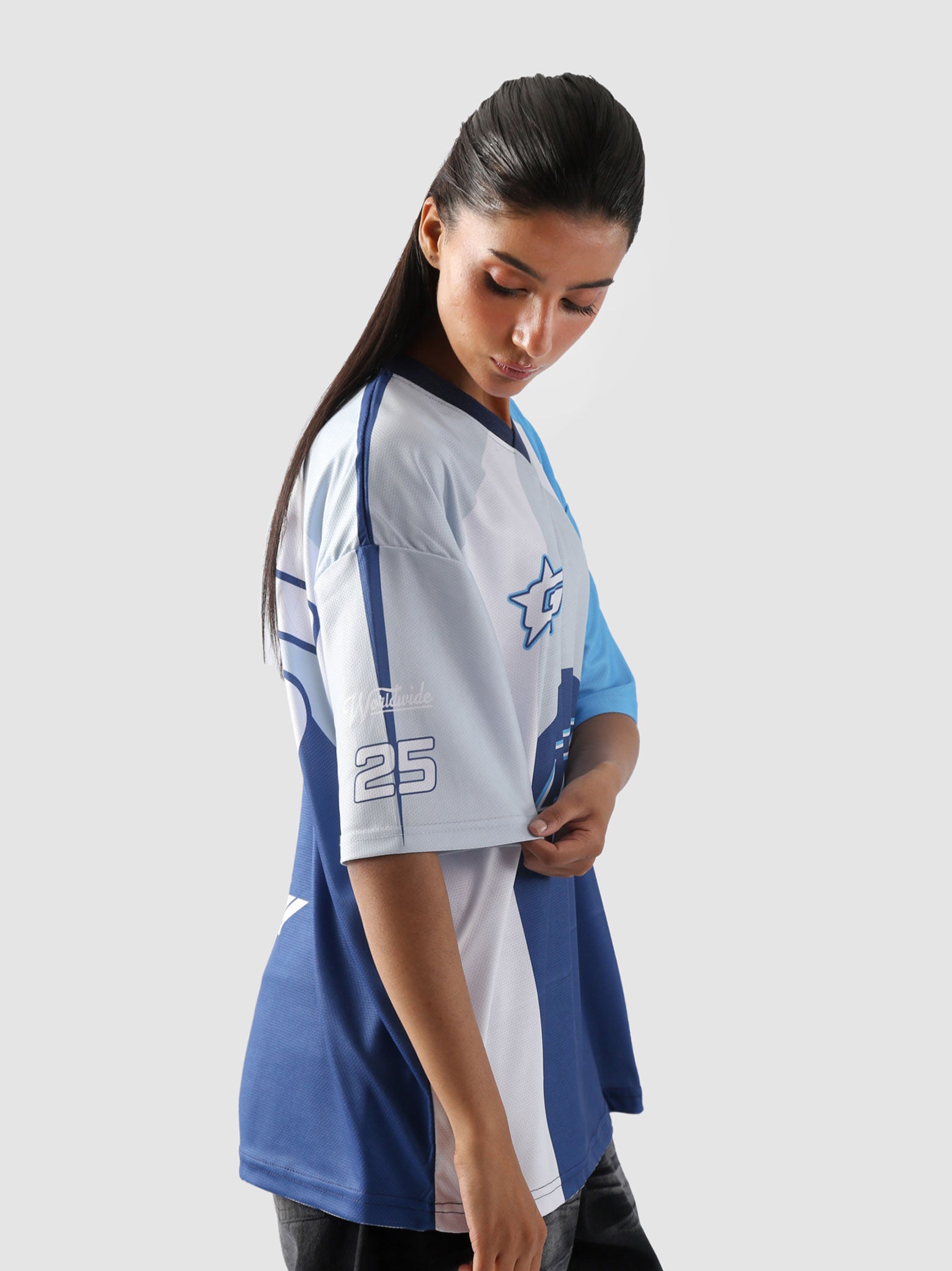 Side view of woman wearing oversized blue and white racing jersey with sleeve number 25 – unisex Groovy Culture streetwear in Pakistan
