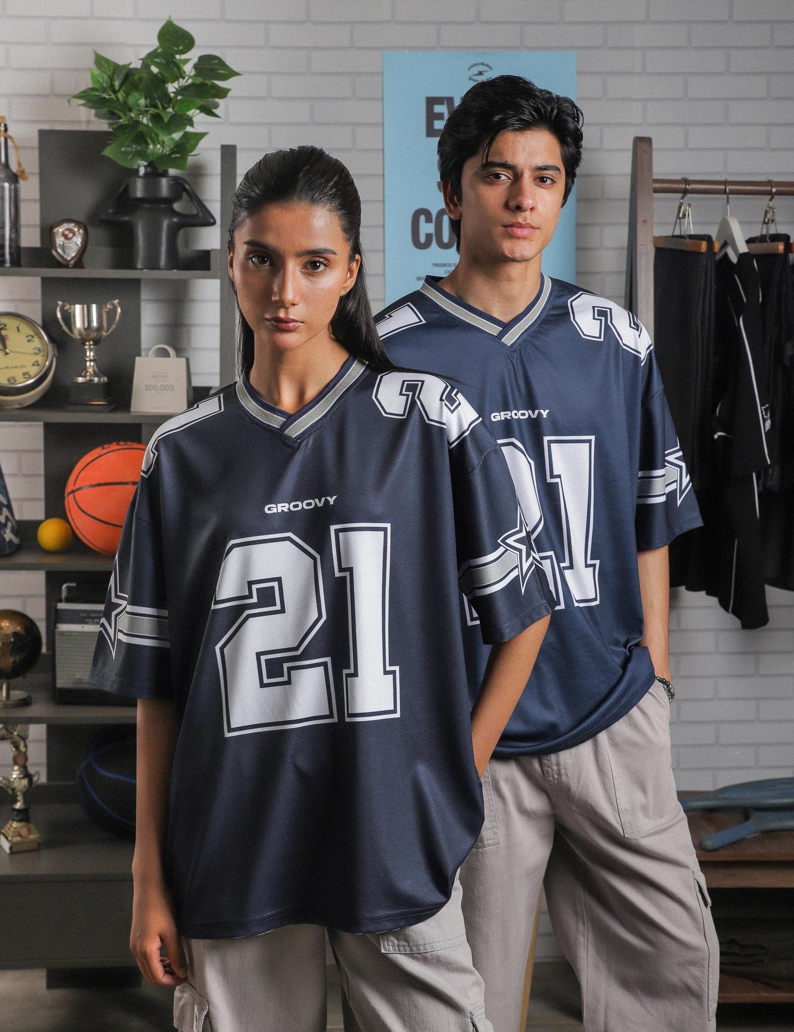 Female and male model both wearing GROOVY All Stars Basketball Jersey, styled with cargo pants, posed in an indoor sports-inspired setup.