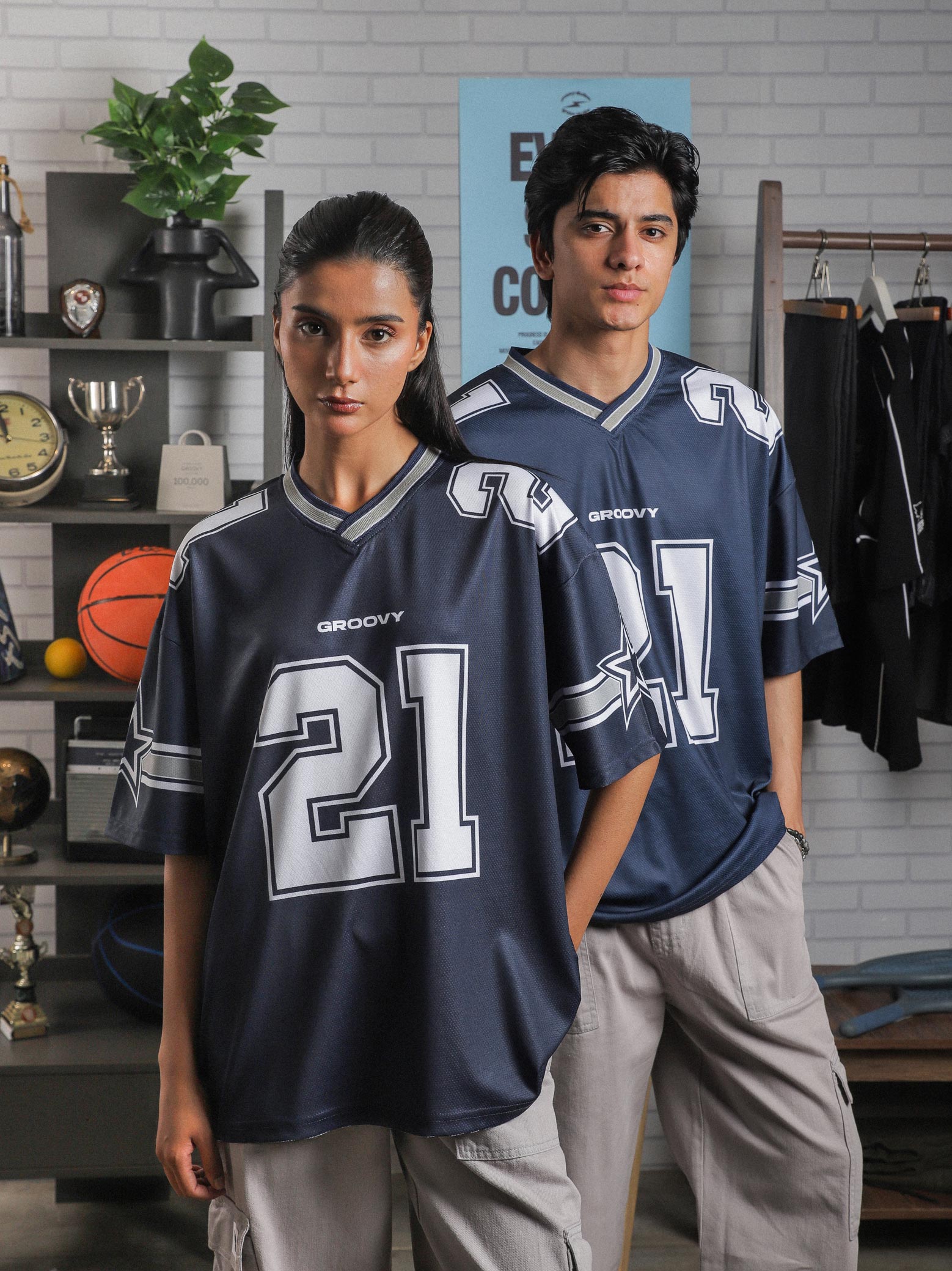 Female and male model both wearing GROOVY All Stars Basketball Jersey, styled with cargo pants, posed in an indoor sports-inspired setup.