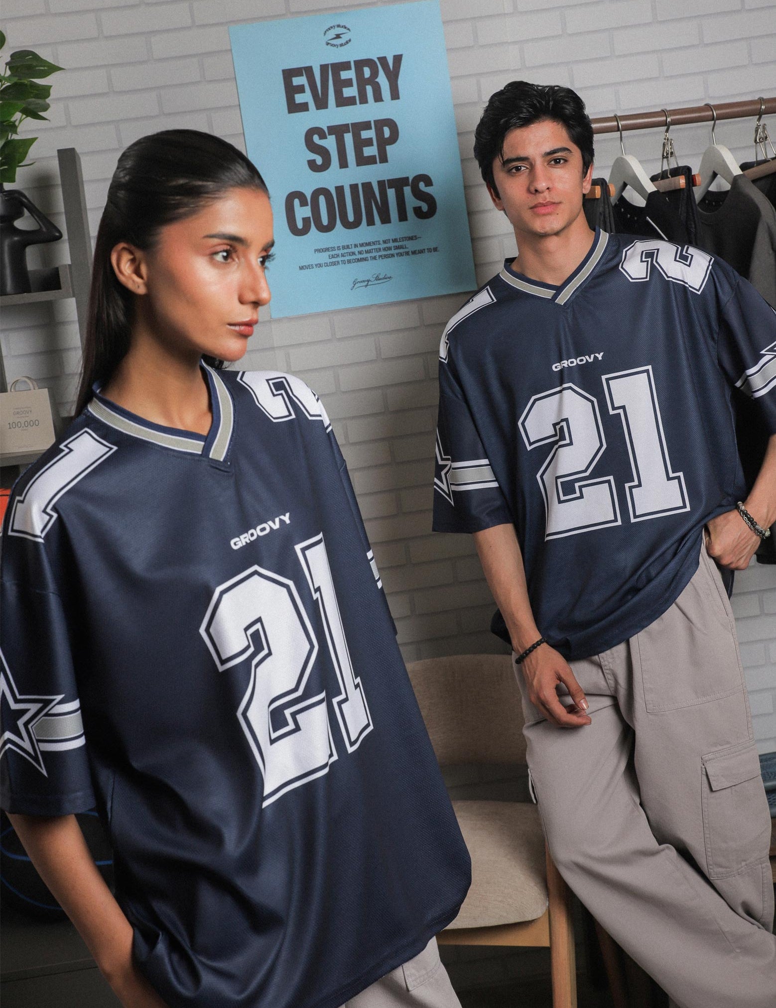 Female and male model both wearing GROOVY All Stars Basketball Jersey, styled with cargo pants, posed in an indoor sports-inspired setup.
