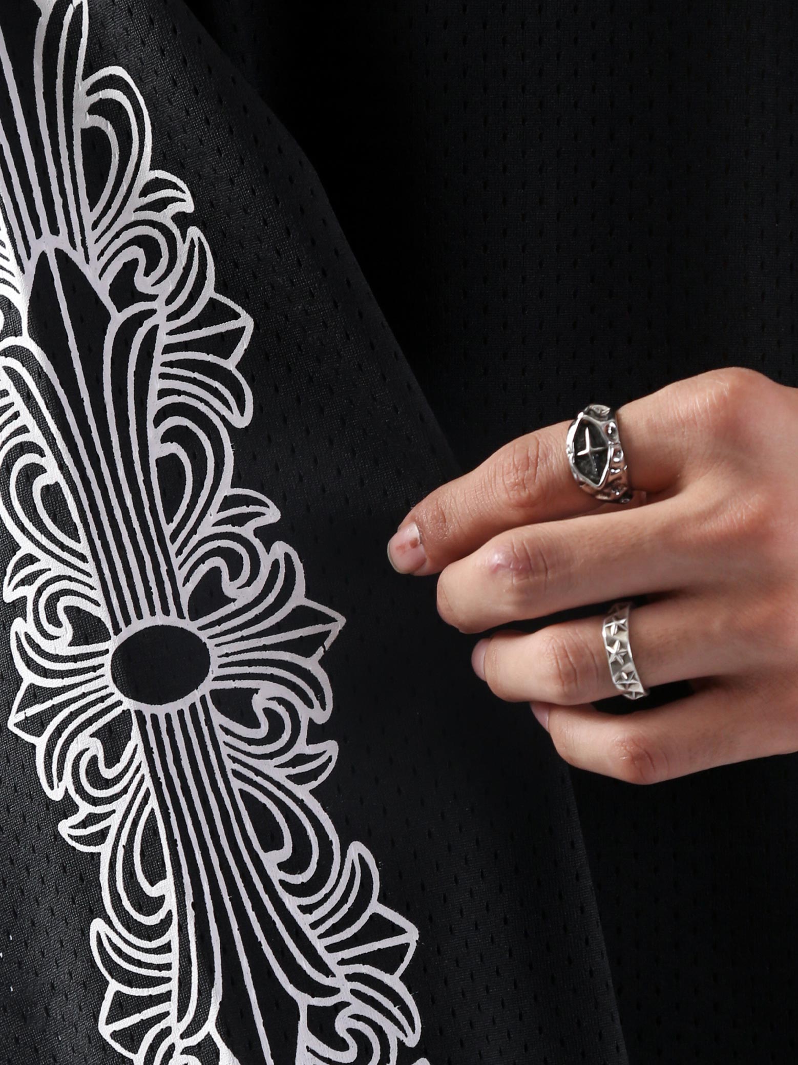 Close-up of the ornate white gothic cross pattern printed on the sleeve of GROOVY’s jersey.