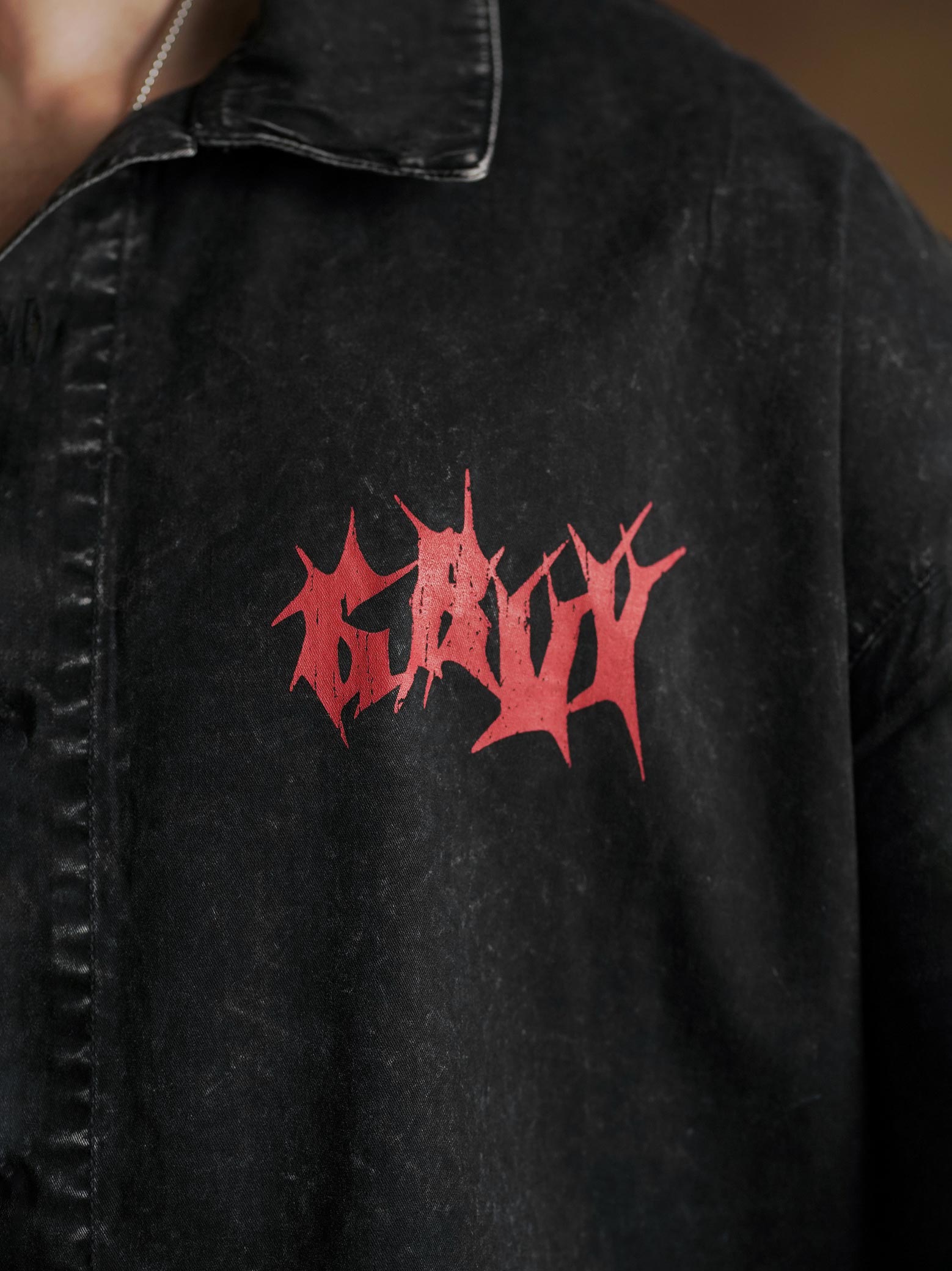 Red screen print close up on washed black denim - GROOVY Pakistan